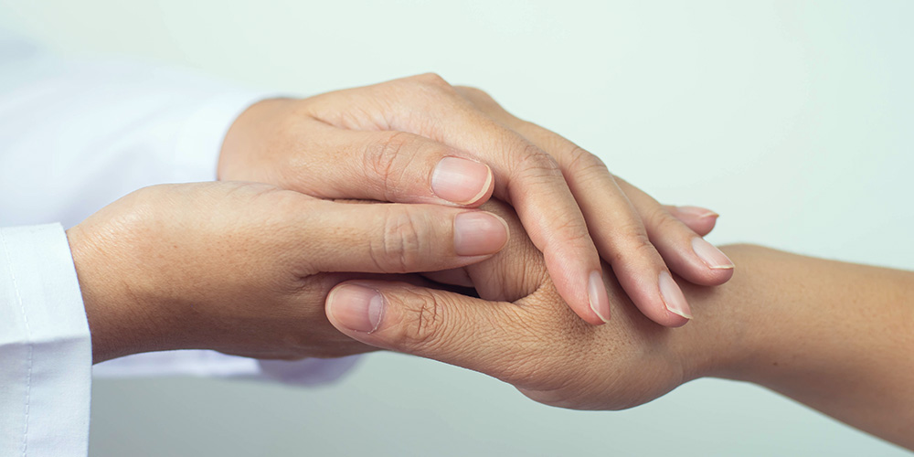 Deux personnes se tenant la main pour se réconforter pour illustrer la conviction de coach dans la démarche de coaching individuel