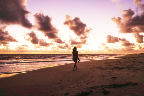 Une silhouette d'une femme marchant sur le sable pour illustrer le coaching et la thérapie existentiels